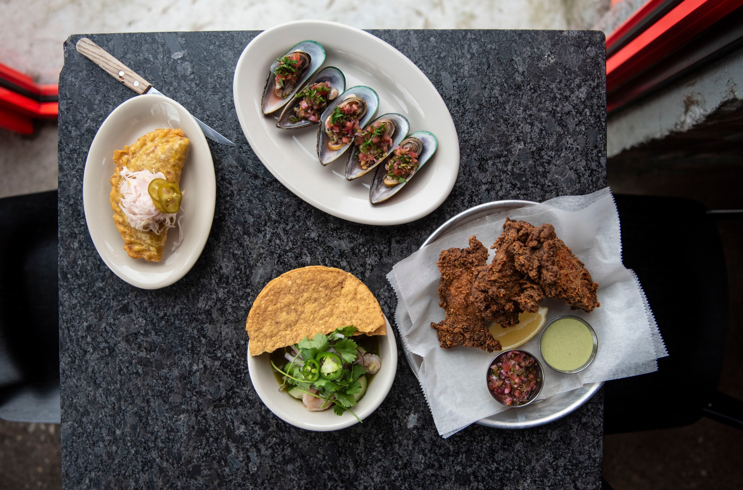 Four dishes served at Puma in Detroit, Michigan shot from above and set on a dark surface.