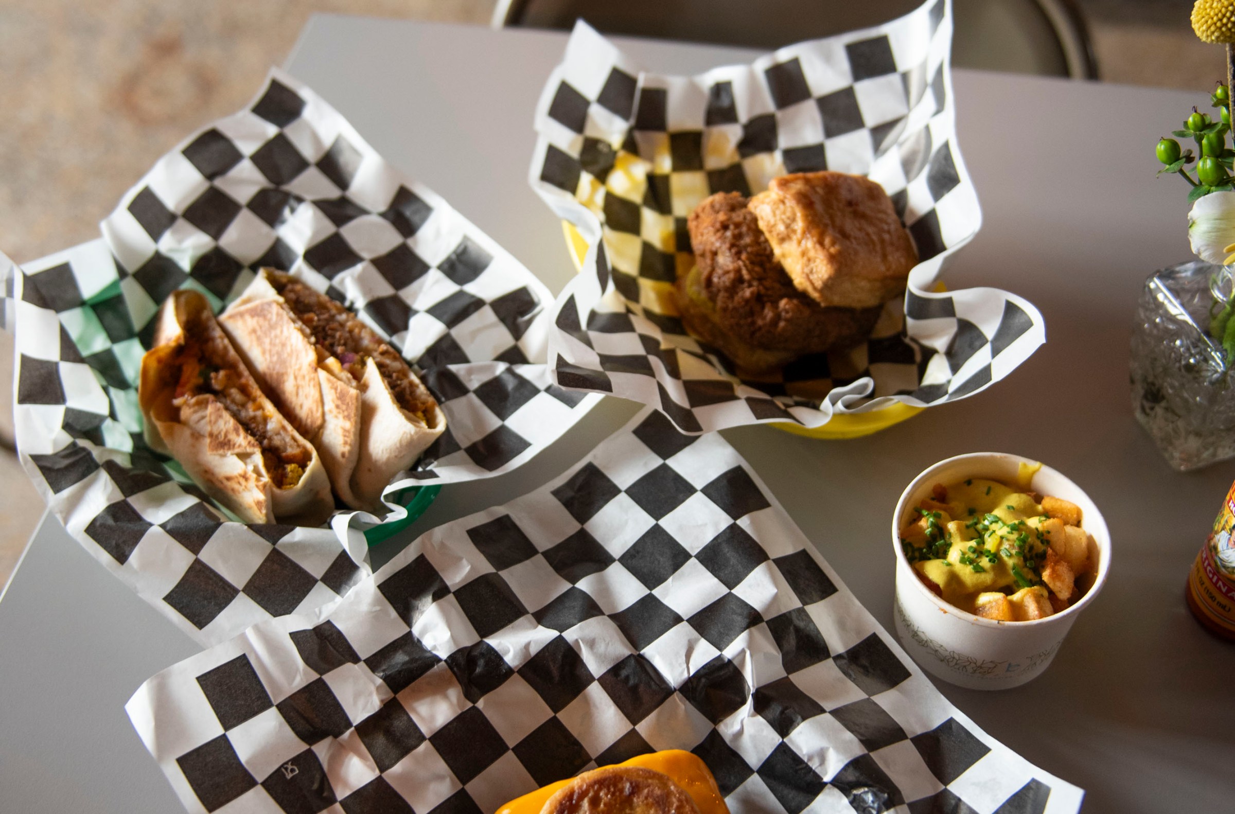 Four dishes offered at Street Beet in Detroit, Michigan set on black and white checked paper on a white surface.