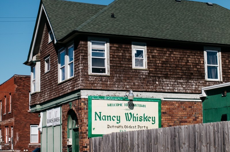 The exterior of Nancy Whiskey’s is covered in wood cladding with a green roof on a sunny, cloudless day.