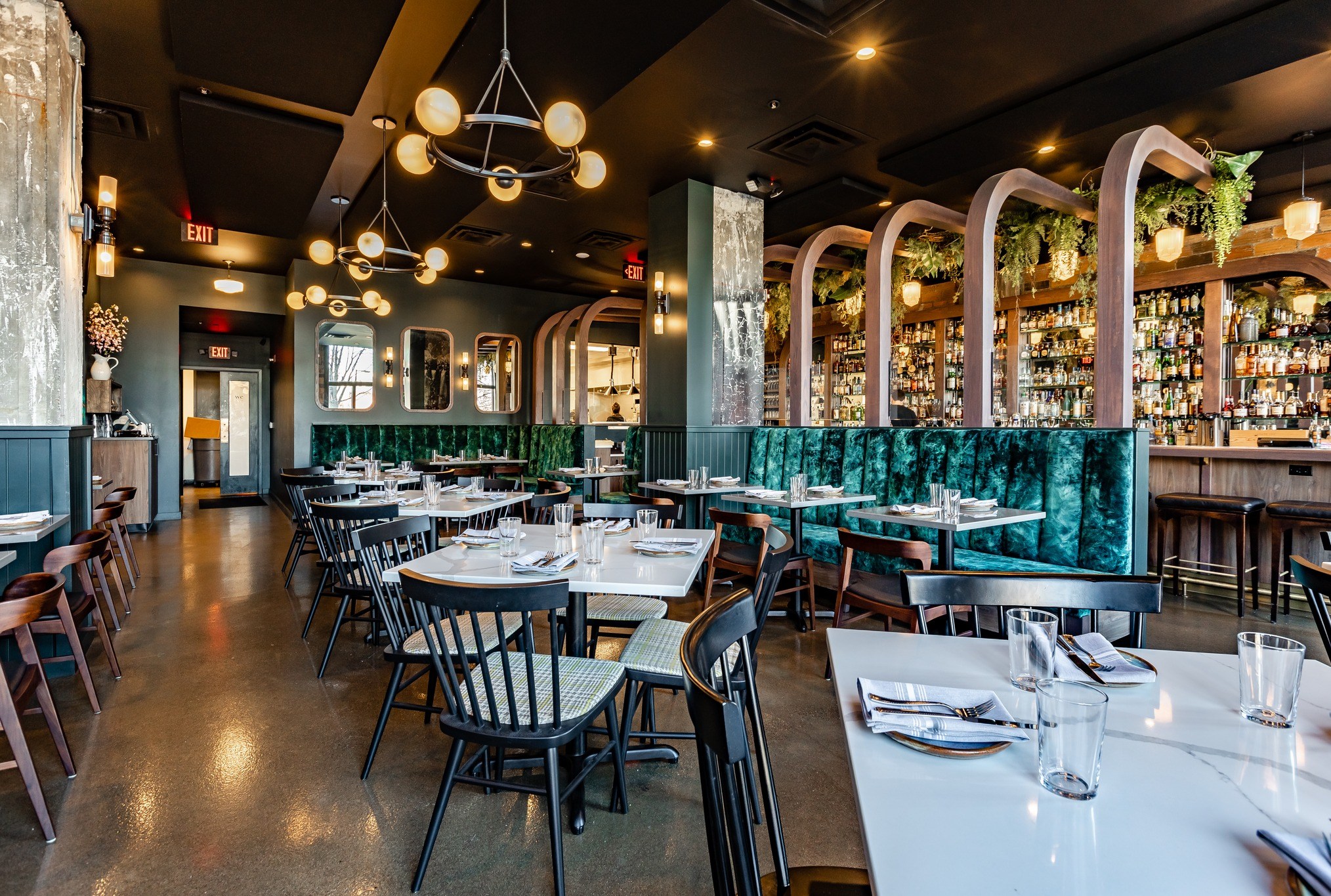 The interior of Bar Pigalle in Detroit, Michigan with white top tables, dark colored chairs, green accents.