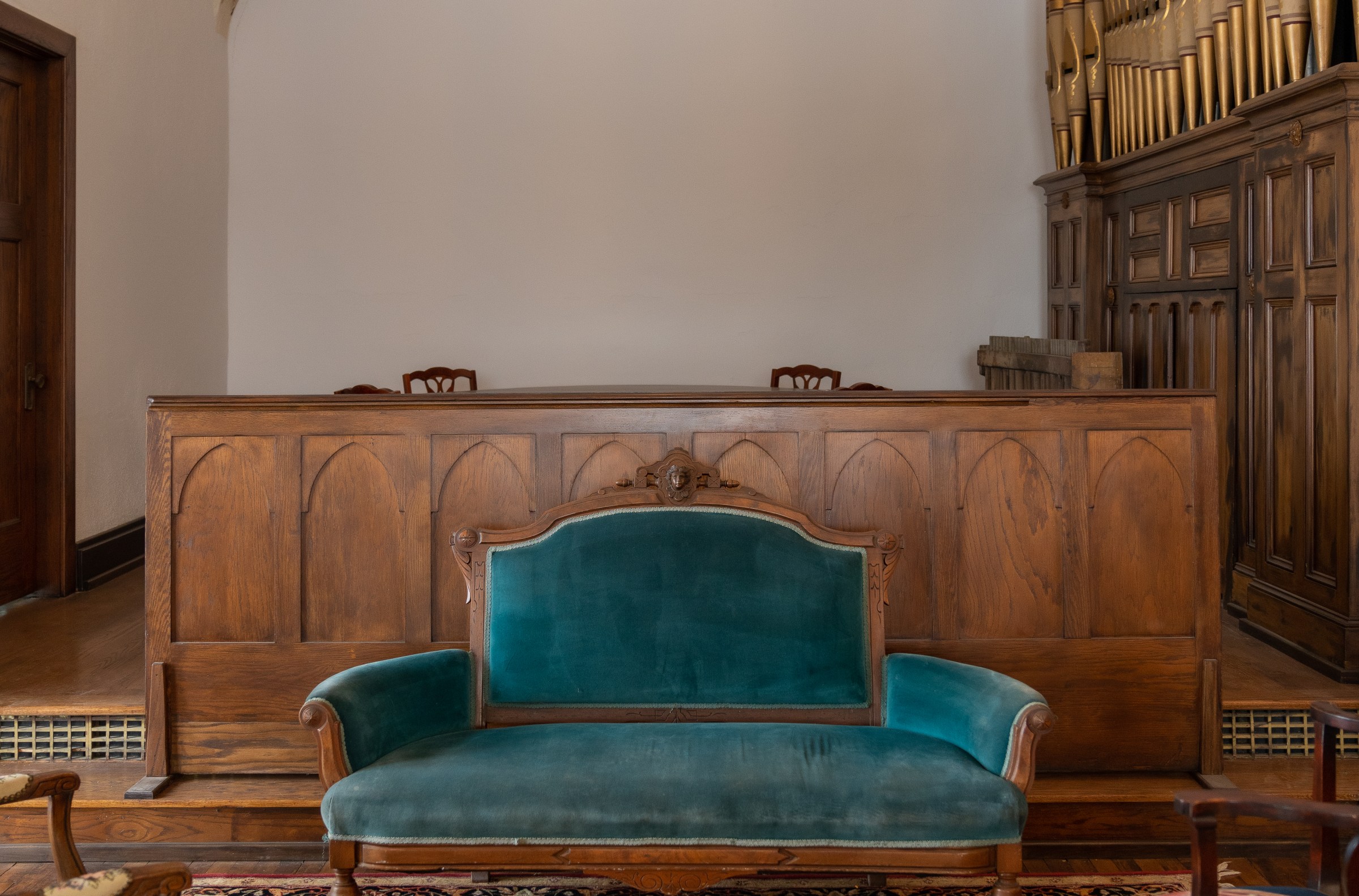 An emerald green sofa in front of a wood counter.