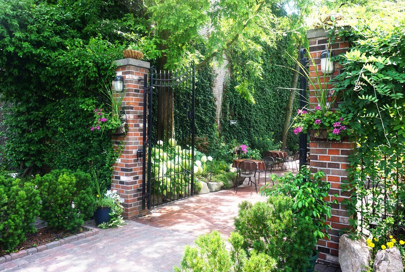 An outdoor patio garden with a brick archway and green foliage.
