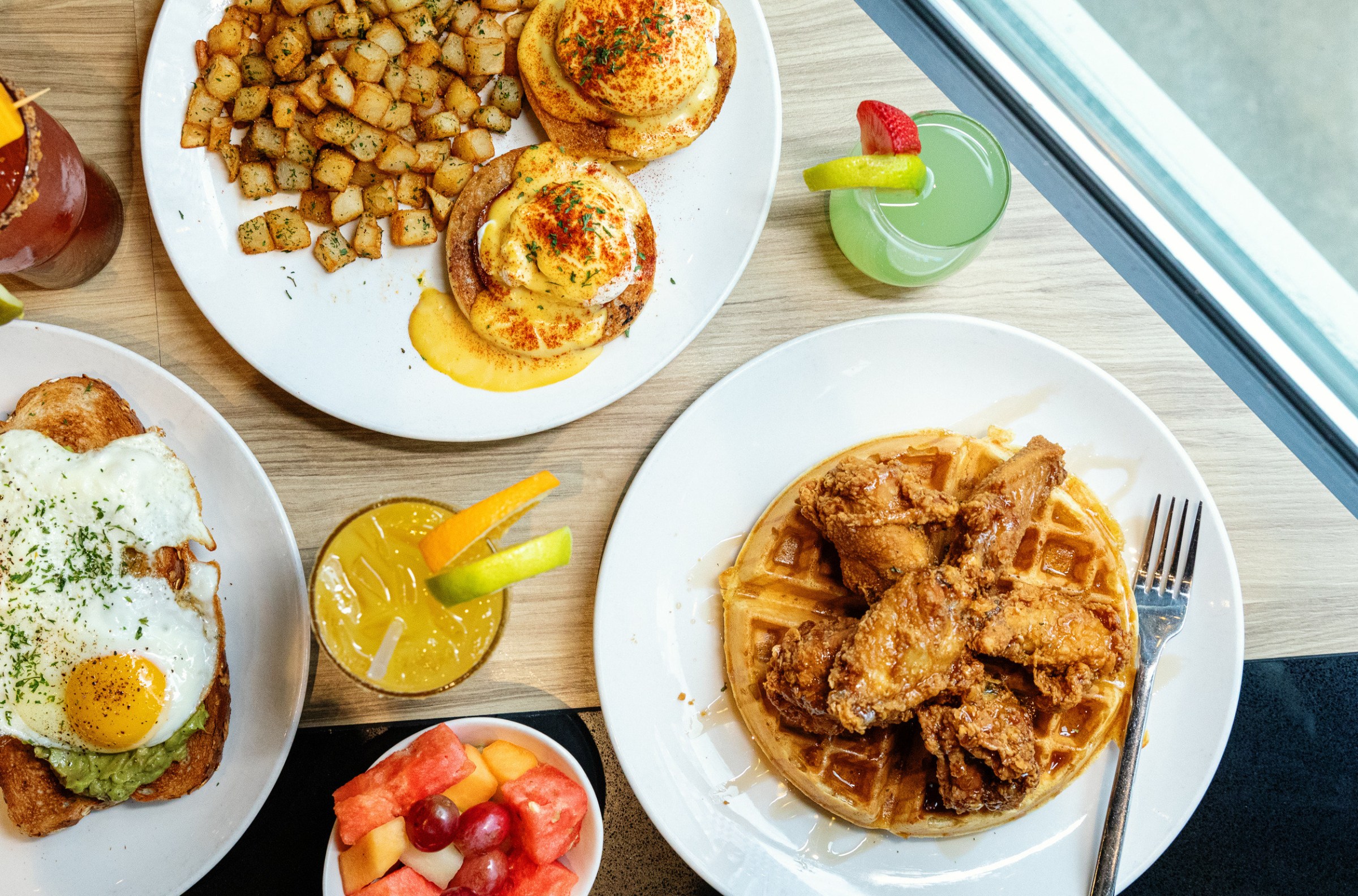 A variety of brunch options including chicken and waffles, eggs benedict, and drinks.