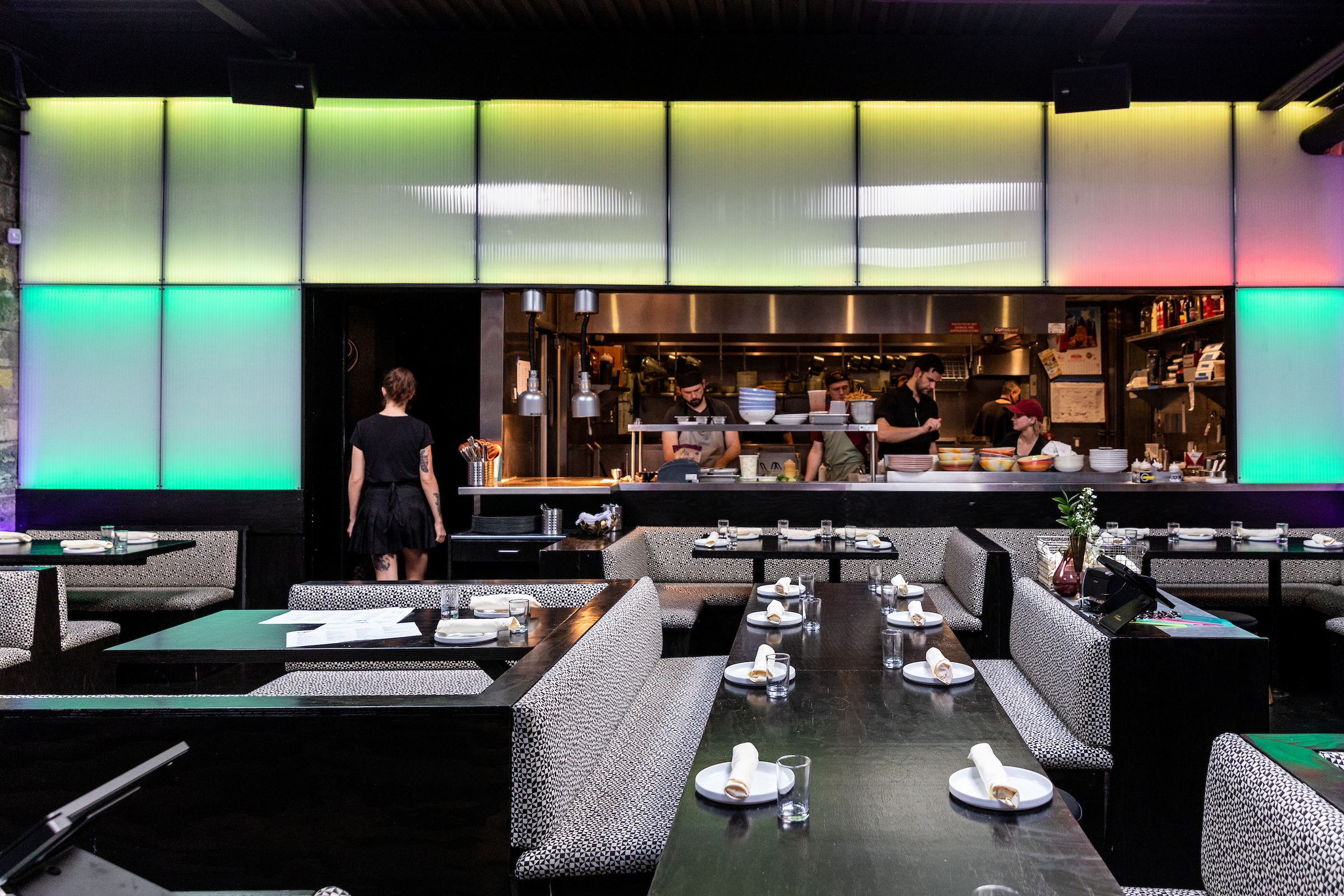 Rainbow-lit plastic wall panels frame the window into the kitchen at Takoi.