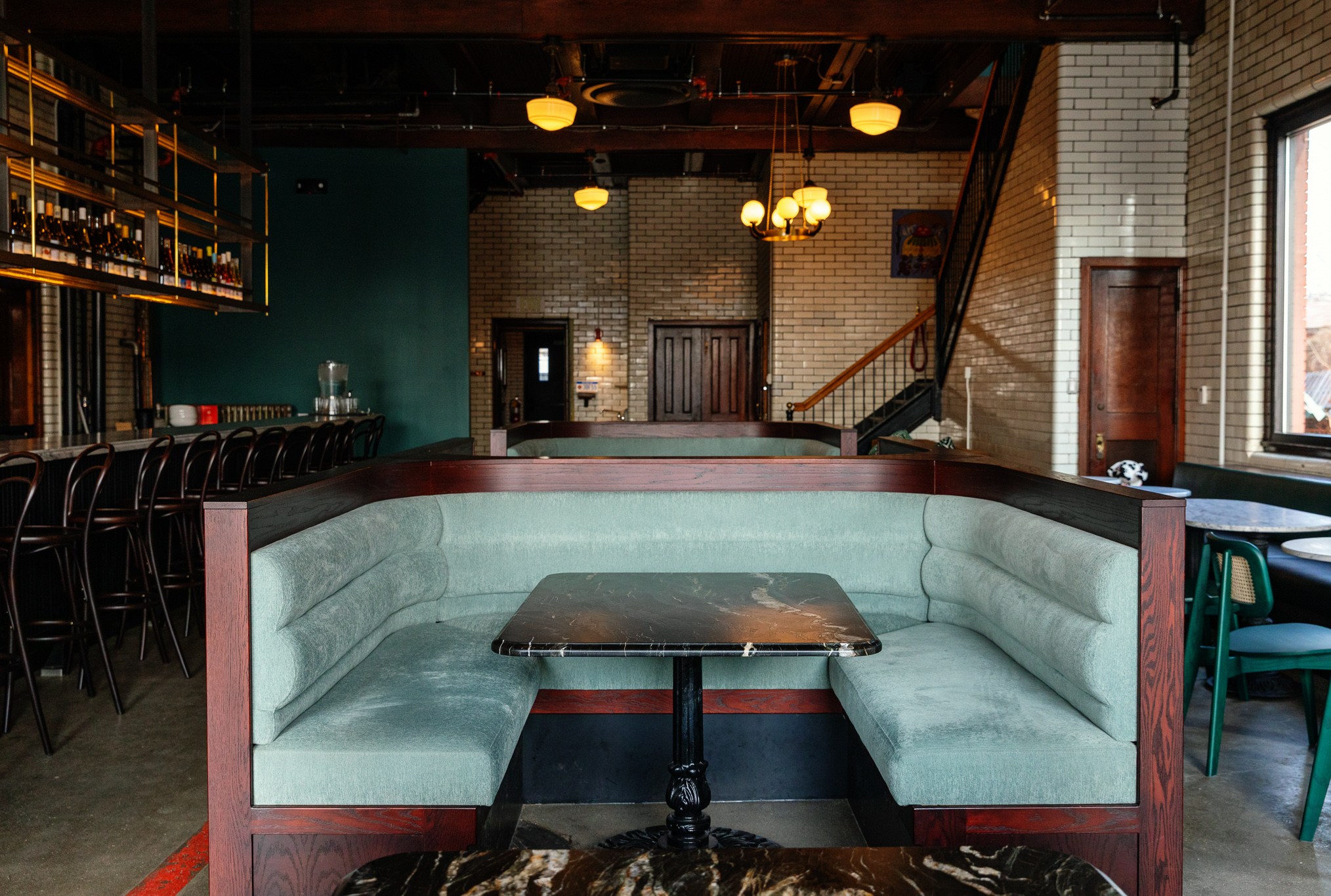 One of the U-shaped booths in green and dark wood with a table in the middle at Ladder 4 Wine Bar in Detroit, Michigan.