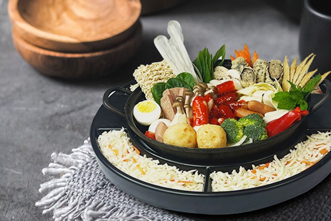 A black round bowl with different food ingredients in it.